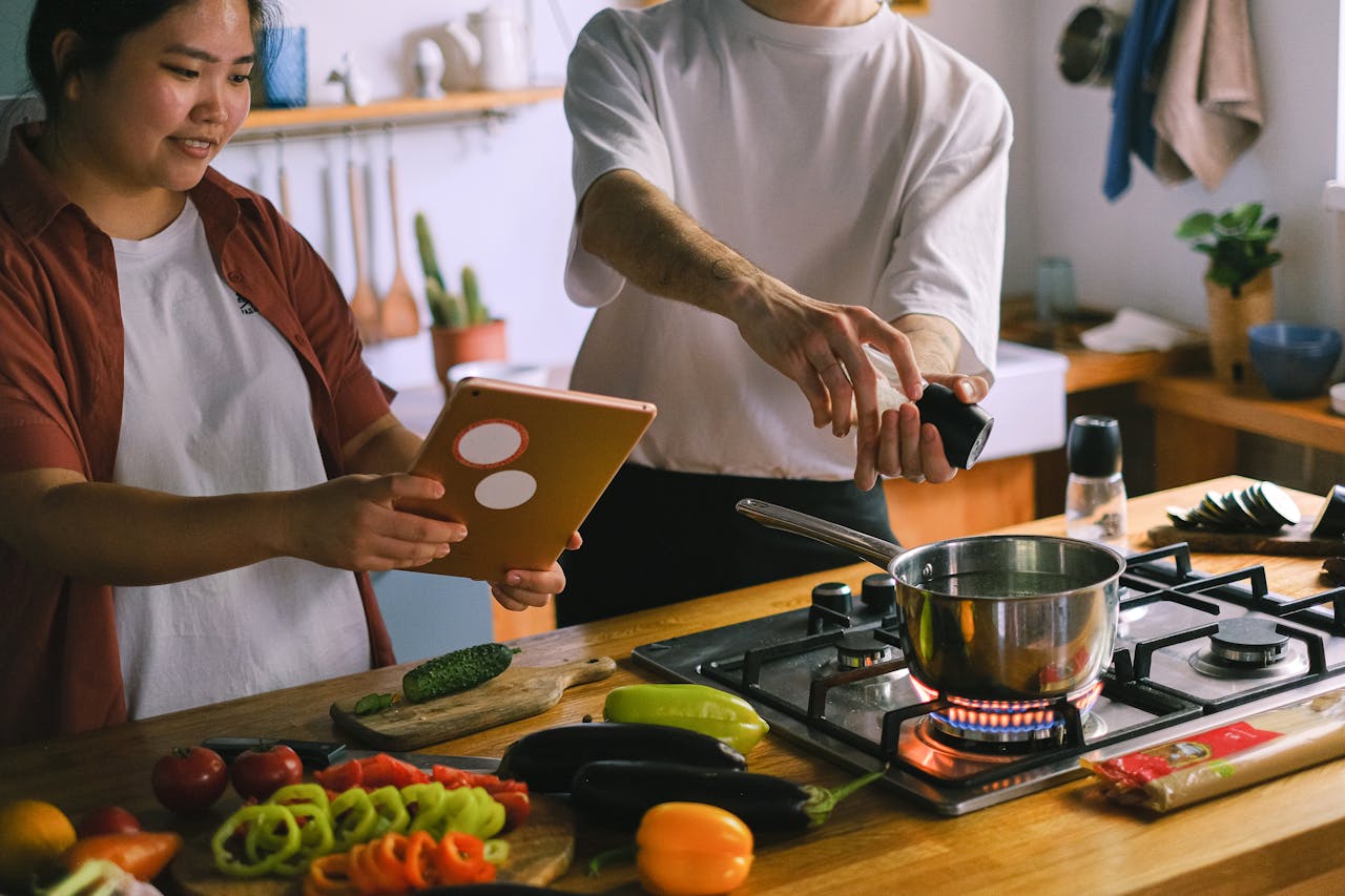 team-04 A happy couple using a tablet while preparing a meal in a stylish kitchen.